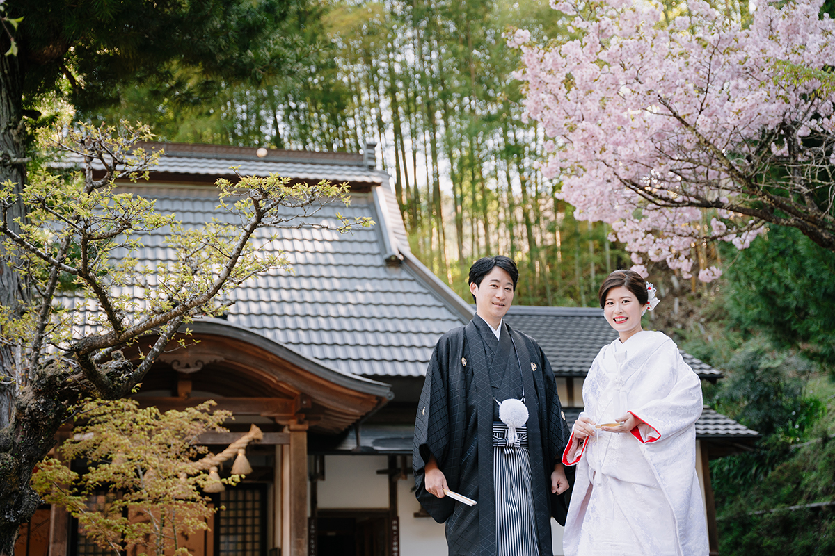 正寿院の境内で赤ふきの白無垢を着た笑顔の新婦と新郎