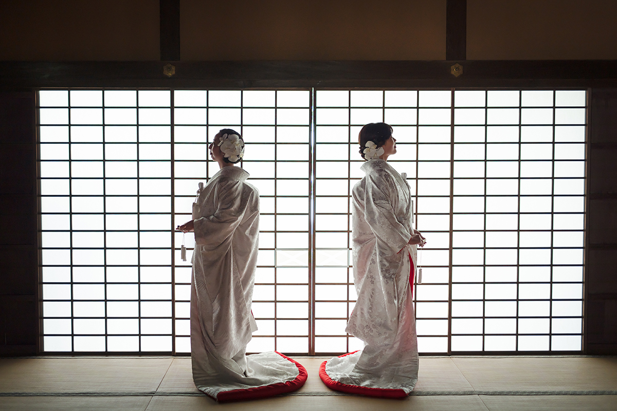 和室で赤ふきの白無垢を着た二人の新婦