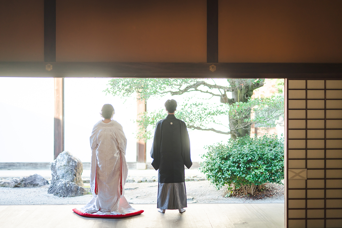 縁側で赤ふき白無垢の新婦と新郎の後ろ姿
