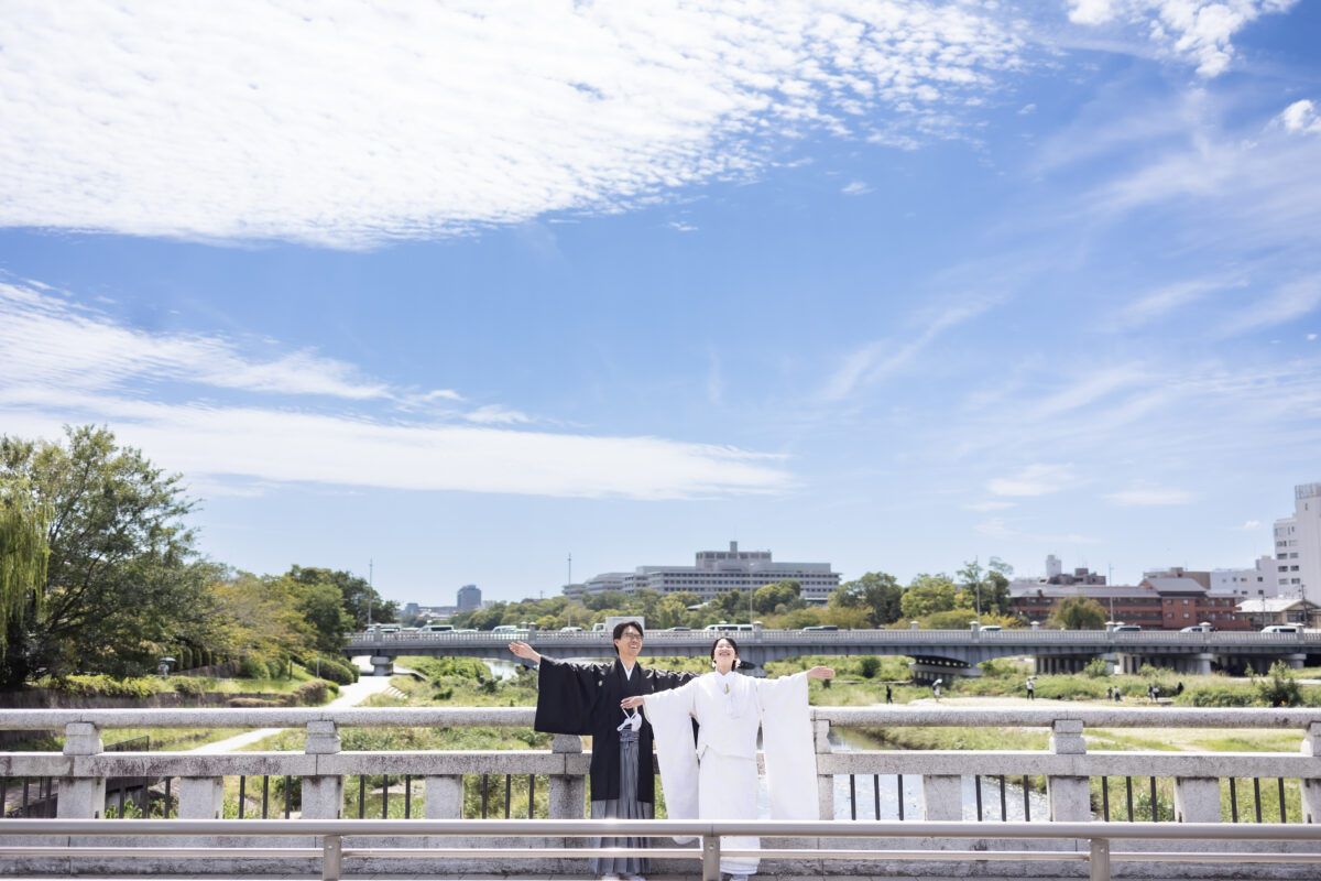 橋の上でラジオ体操をする新郎新婦