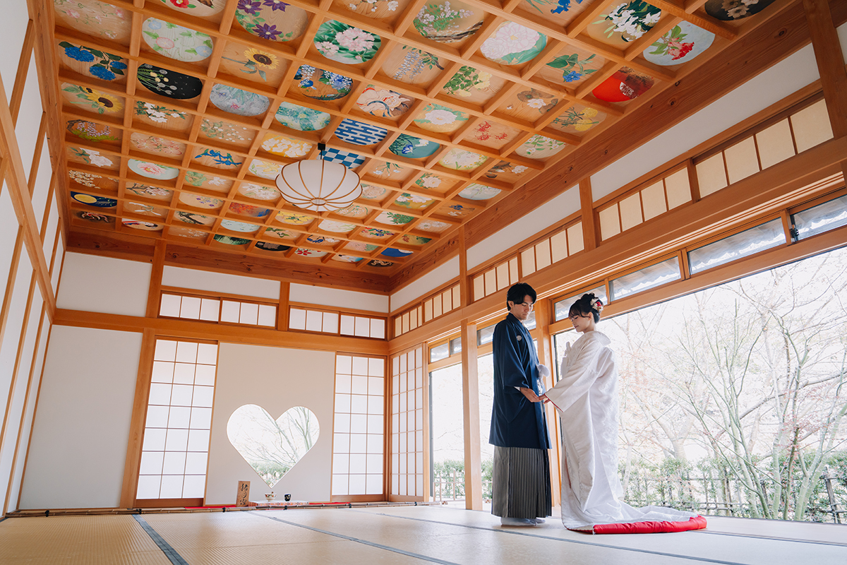 ハートの和室で赤ふきの白無垢姿の新婦と黒紋付姿の新郎が手をつないで向かい合う
