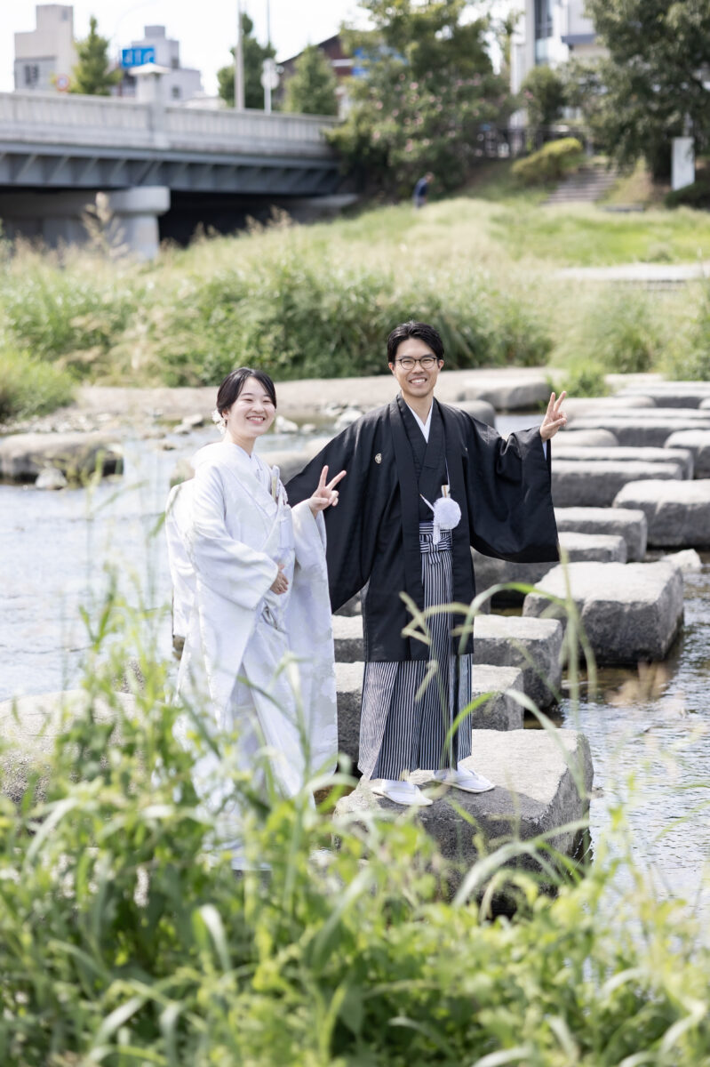 鴨川の飛び石でピースする新郎新婦