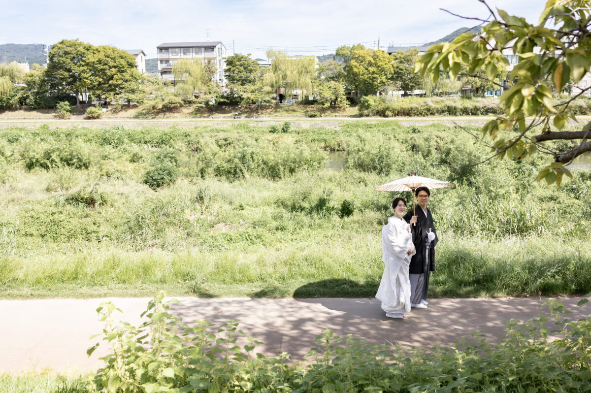 鴨川沿いで和傘を差す新郎新婦
