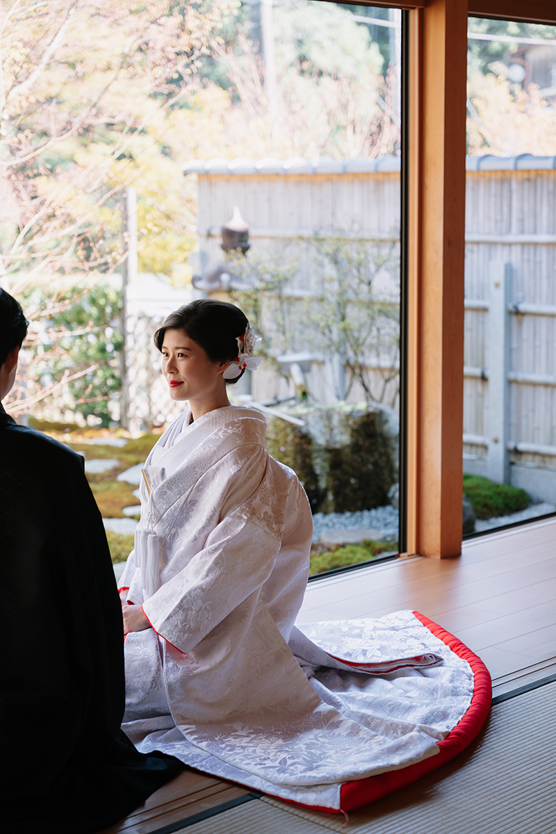 和室の縁側で赤ふきの白無垢を着て座る新婦