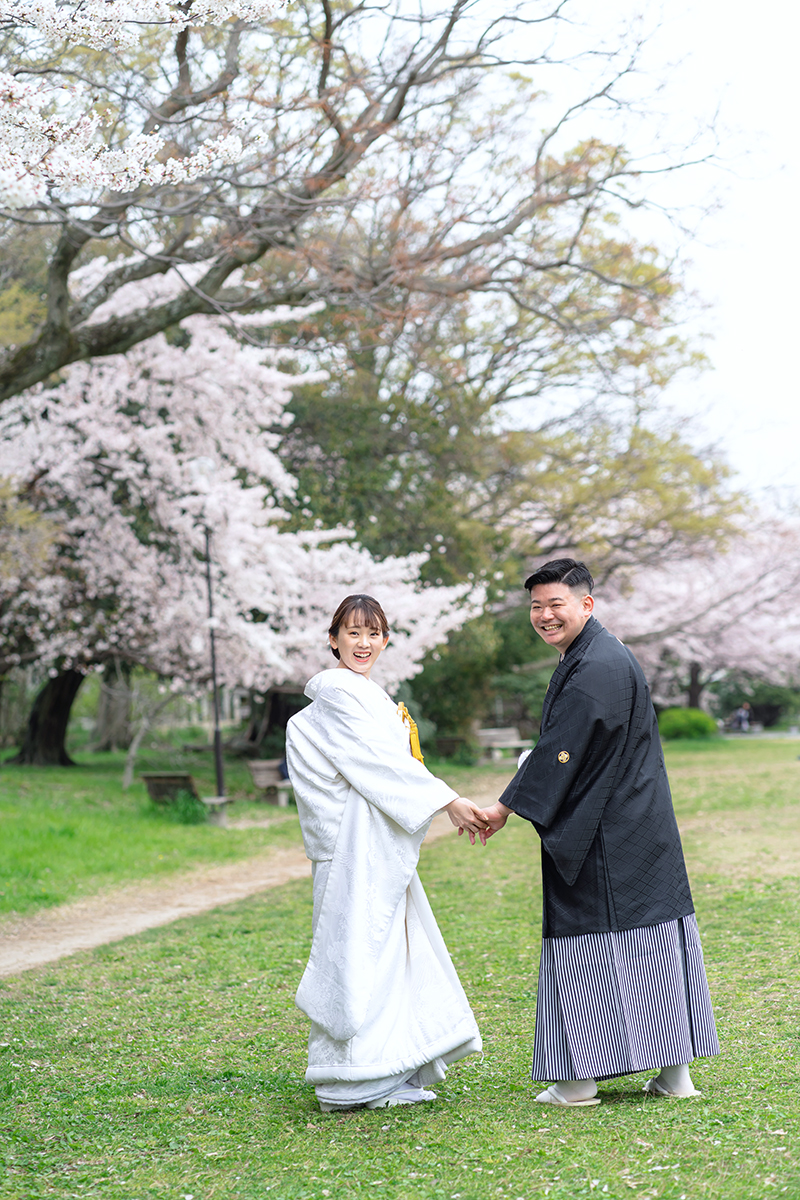 鴨川の前撮り・フォトウェディング「桜の芝生の道で振り返る二人」