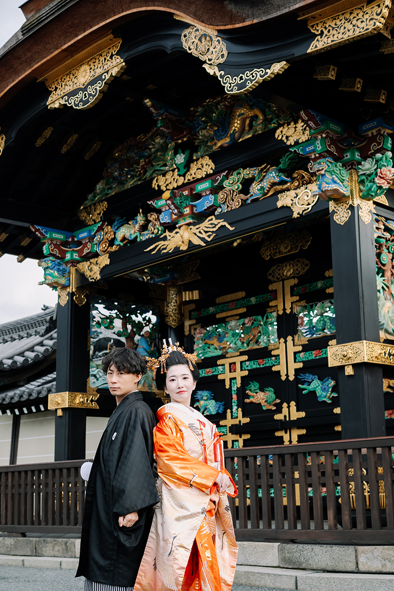 煌びやかな唐門を背に立つ新郎新婦