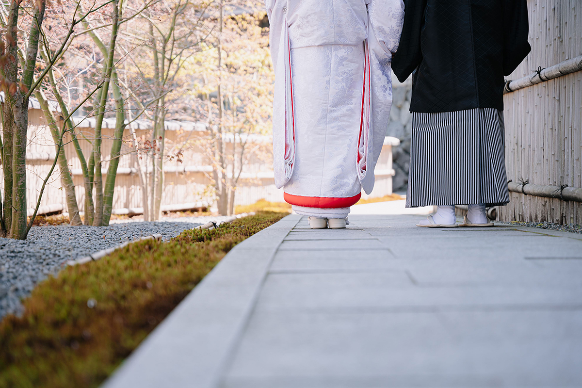 正寿院で手をつなぐ赤ふきの白無垢を着た新婦と新郎の足元の後ろ姿
